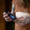 A woman with Tattooed hands holds Foundry Indica CBD Oil.